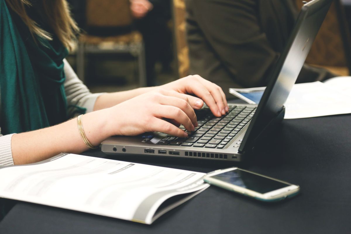 Người viết đang soạn bài content chuẩn SEO trên laptop với tài liệu tham khảo